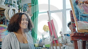 Young cheerful model African American woman posing for group of arts students in studio