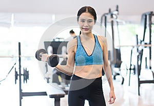Young cheerful smiling woman exercising with dumbbells in gym ,Fitness Concept,Healthy Lifestyle and people concept.