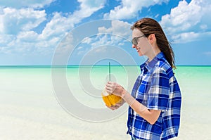 Young cheerful woman with coconut against turquoise sea