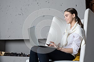 Young cheerful woman content manager or professional writer keyboarding on portable laptop computer, sitting in modern interior ne