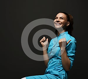Young cheerful woman doctor gynecologist reproductologist in blue working uniform sitting and feeling excited