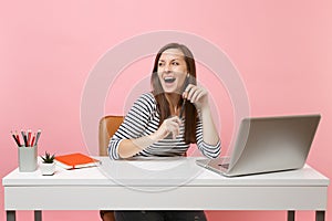 Young cheerful woman with opened mouth hold pencil looking aside sit work at white desk with contemporary pc laptop