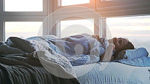 Young cheerful woman Sleeping Cozily in Bed by the window