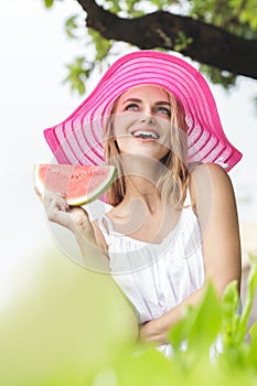 Young cheerful woman wearing pink sunhat with watermelon