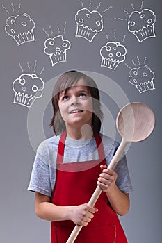 Young chef with apron and large wooden spoon