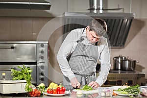 Young chef cutting beet on a white cutting board closeup. Cooking in a restaurant kitchen