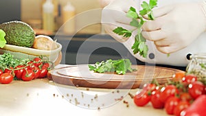 Young chef is cutting herbs and parsley in a modern kitchen. The man prepares food at home. Cooking healthy food.