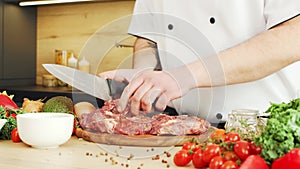 Young chef is cutting meat in a modern kitchen. The man prepares food at home. Cooking healthy food.