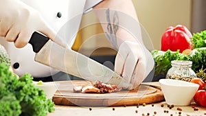 Young chef is cutting octopus in a modern kitchen. The man prepares food at home. Cooking healthy food.