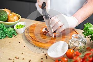 Young chef is cutting octopus in a modern kitchen. The man prepares food at home. Cooking healthy and tasty food.