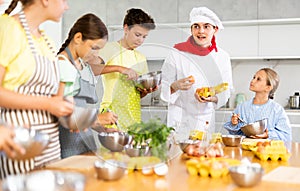 Young chef giving culinary classes to group of interested tweens