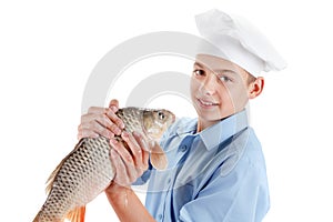 Young chef holding a fish carp on white background