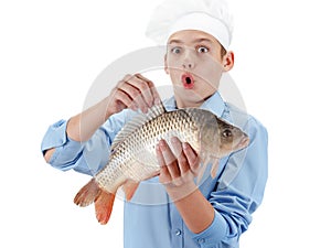 Young chef holding a fish carp on white background