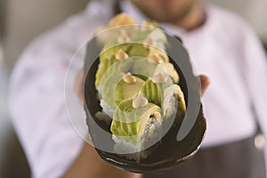 Young chef holding a plate of sushi