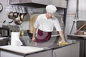 Young chef in kitchen cleaning working table, after closing restaurant