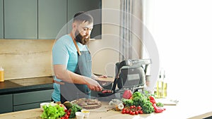 Young chef preparing grilled meat steak in a modern kitchen. The man prepares food at home. Cooking healthy food.