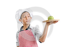 Young chef serving green apple on wooden tray