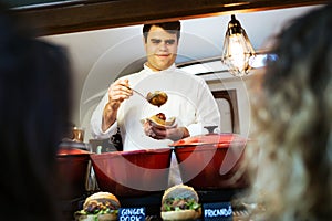 Young chef serving meatballs to two pretty girls in a food truck.