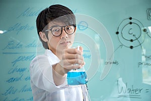 Young chemist is holding the glass conical flask with a blue liquid chemical solution