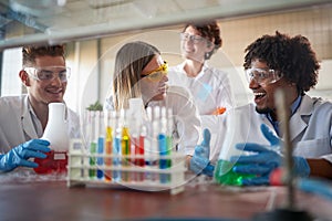 Young chemistry students having a good time in a laboratory while working with colorful chemical. Science, chemistry, lab, people