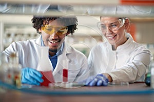 Young chemistry students in a protective gear like working with colorful chemicals in the university laboratory. Science,