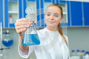 Young chemistry teacher in school laboratory work standing holding bulb close-up