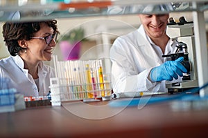 Young chemistry university colleagues enjoying working with a microscope in a laboratory. Science, chemistry, lab, people