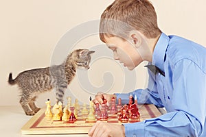 Young chessplayer with kitten plays chess.