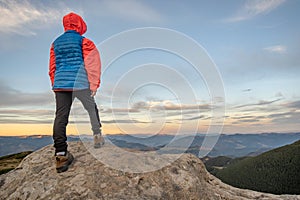 Young child boy hiker standing in mountains enjoying view of amazing mountain landscape