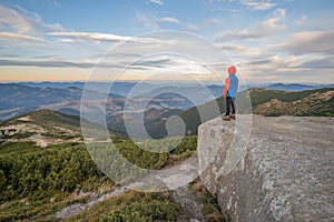 Young child boy hiker standing in mountains enjoying view of amazing mountain landscape