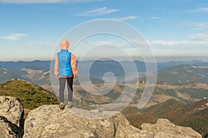 Young child boy hiker standing in mountains enjoying view of amazing mountain landscape