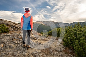 Young child boy hiker standing in mountains enjoying view of amazing mountain landscape