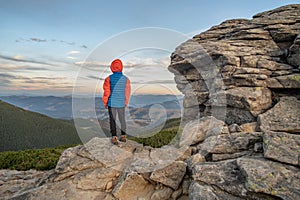 Young child boy hiker standing in mountains enjoying view of amazing mountain landscape