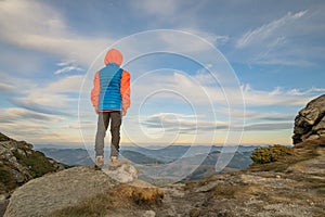 Young child boy hiker standing in mountains enjoying view of amazing mountain landscape