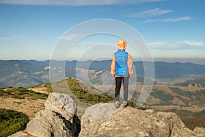 Young child boy hiker standing in mountains enjoying view of amazing mountain landscape