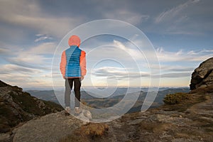 Young child boy hiker standing in mountains enjoying view of amazing mountain landscape