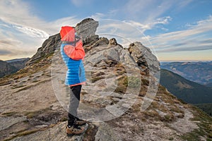 Young child boy hiker taking pictures in mountains enjoying view of amazing mountain landscape