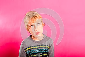 Young child boy making strange faces, rolling his eyes in a grotesque way