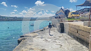 Young child, boy running on the coast. Qawra, Malta