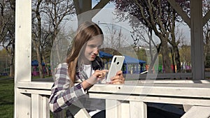 Young Child Browsing Internet on Smart Phone in Park, Adolescent Kid Playing Smartphone, Teenager Girl use Devices Outdoor