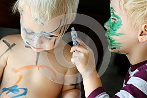 Young Child Coloring Baby Brother's Face