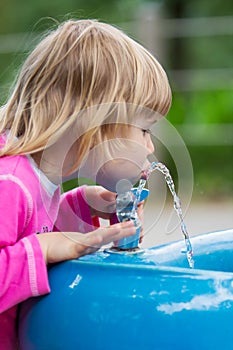 Young child drink water from public fountain