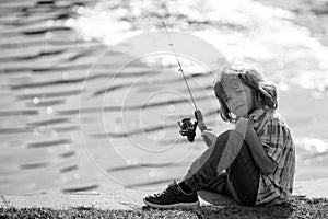 Young child fisher at river. Kid fishing, summer outdoor leisure activity. Little boy angling at river bank with rod.