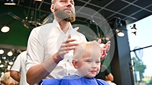 Young child getting haircut in modern barbershop.