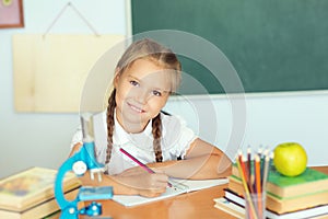 Young child girl drawing or writing with colorful pencils in not