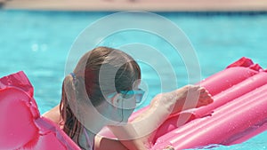 Young child girl falling in water from inflatable air mattress in swimming pool while swinnimg during tropical vacations
