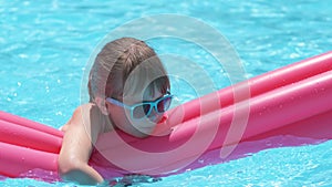 Young child girl falling in water from inflatable air mattress in swimming pool while swinnimg during tropical vacations