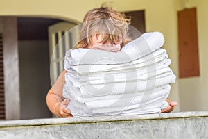 Young child girl holding rolled beach or spa towels on outd