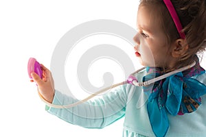 Young child girl with a phonendoscope playing doctor. Healthcare and medicine concept.