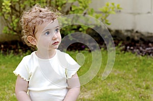 Young child, girl, in plain light top daydreaming.